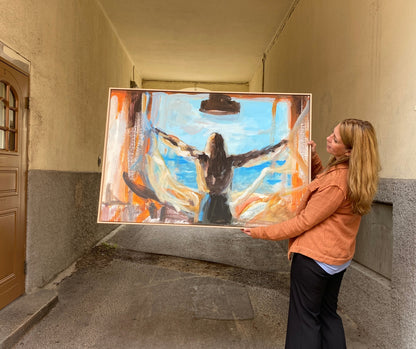 Artist Ingela Johansson holding her painting Open as a canvas print with oak frame