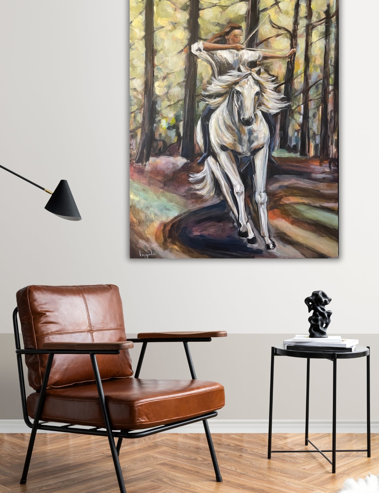 Original painting ‘Power’ by Ingela Johansson hanging in a stylish interior with a brown leather chair, highlighting the dynamic horse, a woman and an archer scene.
