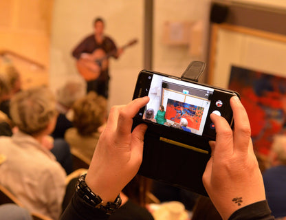 A photo from Sinnen at Naturum howing Krisna Patra singing in the photo artist Ingela Johansson and her red and blue painting the Red Drop.