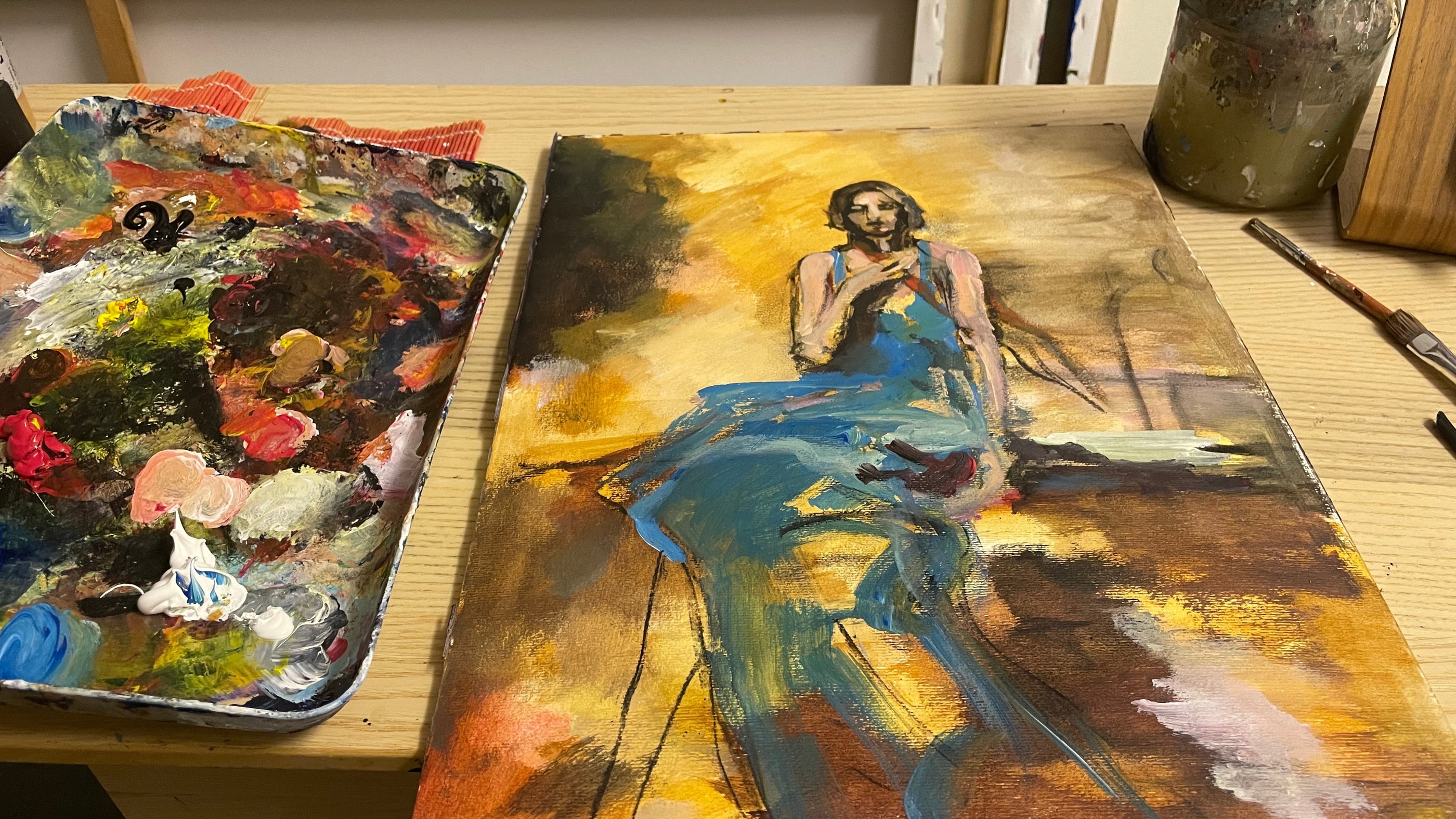 Artist Ingela Johansson painting an original acrylic and charcoal artwork on paper in her studio, with colour palette and works in progress visible